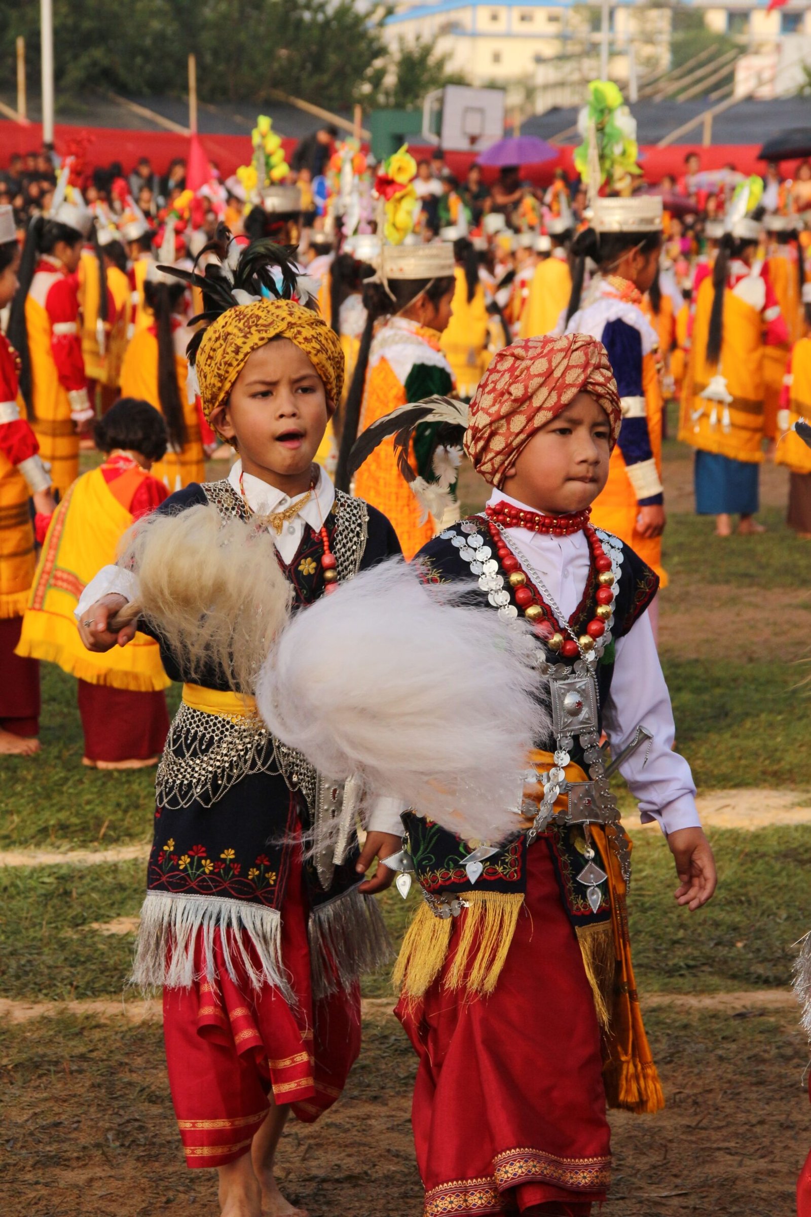 Young boys in traditional Indian attire performing at a cultural festival outdoors.