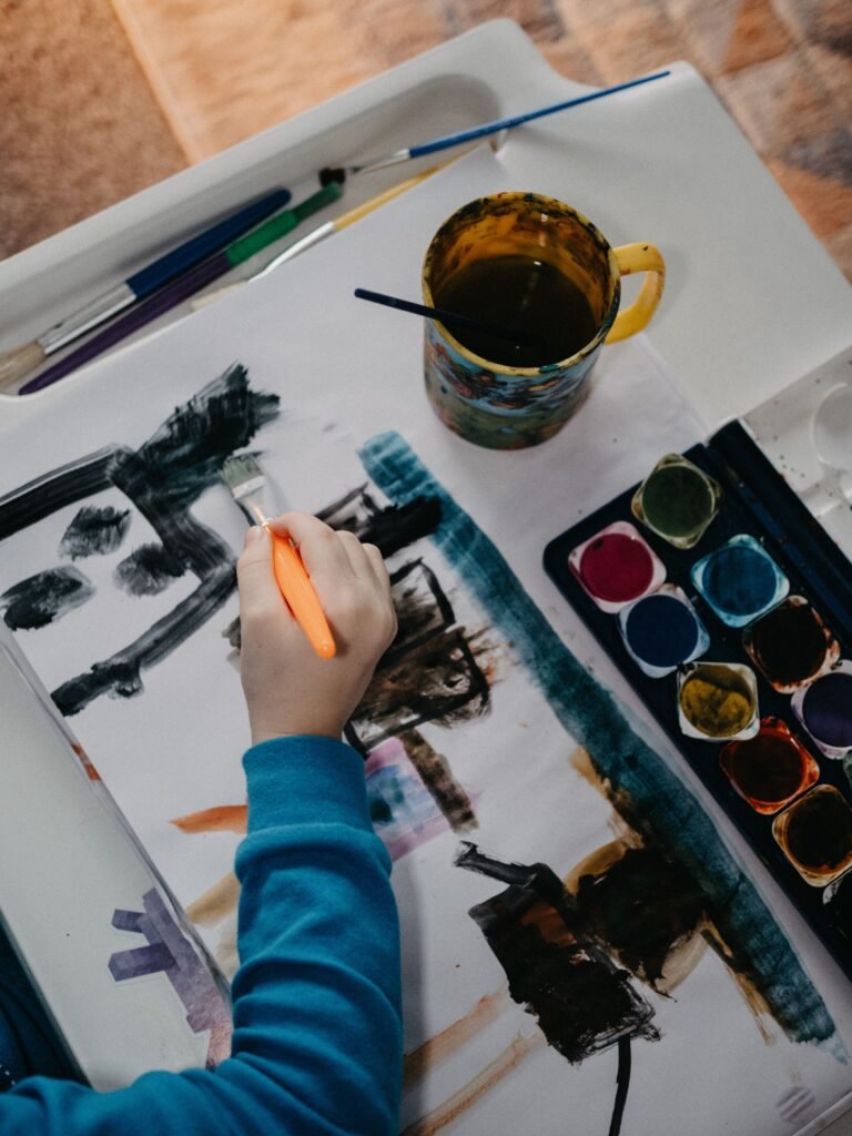 A child engaging in watercolor painting on a canvas with art supplies.